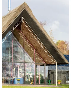 Contemporary glass-fronted thatched house with wooden beams and open living space.